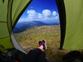 Woman lying in tent with a view of mountain and sky Royalty Free Stock Photo