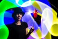 Woman magician in a black hat against a background of multi-colored light. Magic, sorcery, horoscope concept Royalty Free Stock Photo