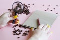 Woman with magnifier, notepad and pen examines quality of roasted coffee beans. Concept of coffee quality examination. Analysis