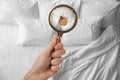 Woman with magnifying glass detecting bed bugs in bedroom Royalty Free Stock Photo