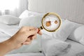 Woman with magnifying glass detecting bed bugs in bedroom Royalty Free Stock Photo