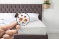 Woman with magnifying glass detecting bed bugs on mattress, closeup. Royalty Free Stock Photo