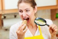 Woman with magnifying glass eating potato. Royalty Free Stock Photo