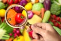 Woman with magnifying glass exploring vegetables, closeup. Poison detection