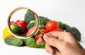 Woman with magnifying glass exploring vegetables, closeup. Poison detection