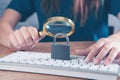 Woman magnifying glass looking at keyboard with lock