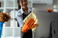 Woman maid cleaning and wiping the computer with microfiber cloth in office Royalty Free Stock Photo