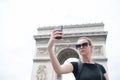 Woman make selfie with phone at arc de triomphe in paris, france. Woman with smartphone at arch monument. Vacation and sightseeing Royalty Free Stock Photo