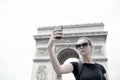 Woman make selfie with phone at arc de triomphe in paris, france. Woman with smartphone at arch monument. Vacation and Royalty Free Stock Photo