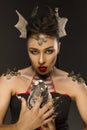 Woman with make up of dragon holding dragon egg in hands over dark background. Fantasy, Halloween and magic concept.