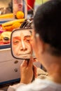 A woman make up the eyebrow with mirror.