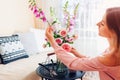 Woman makes bouquet of roses and foxgloves flowers in vase on table at home. Interior and summer decor
