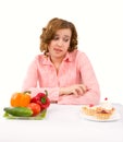 Woman makes choice of cakes and vegetables Royalty Free Stock Photo