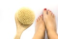 Woman makes massage legs with wooden soft massage brush for body and legs on white background. Anti cellulite home spa treatment Royalty Free Stock Photo