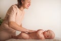 A woman makes a massage to a newborn. Baby care concept at home, massage, colic, children teething