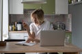 Unemployed woman reads notebook writing list of contacts, looking for vacancies on laptop on table