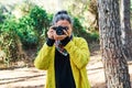 Woman makes photos with analog reflex camera looking at camera in forest
