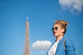 Woman with makeup and sunglasses in front of blue sky and top of Eiffel Tower on background. Stylish Parisian concept Royalty Free Stock Photo