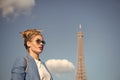 Woman with makeup and sunglasses in front of blue sky and top of Eiffel Tower on background. Stylish Parisian concept Royalty Free Stock Photo