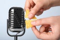 Woman making ASMR sounds with microphone and nacho chip on grey background, closeup