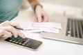 Woman making audit of household spendings at home, using calculator