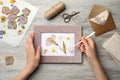 Woman making beautiful herbarium with pressed dried flower at wooden table, top view Royalty Free Stock Photo