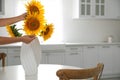 Woman making bouquet of sunflowers in kitchen, closeup. Space for text Royalty Free Stock Photo