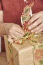 Woman making a bow with a decorative ribbon for decorating a Christmas gift Royalty Free Stock Photo