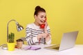 Woman making call on landline phone working on laptop sitting at office pointing at notebook display Royalty Free Stock Photo