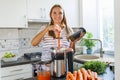 A woman making carrot juice from fresh carrots with a home juicer in the kitchen Royalty Free Stock Photo