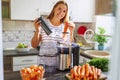 A woman making carrot juice from fresh carrots with a home juicer in the kitchen Royalty Free Stock Photo