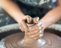 Woman making ceramic pottery on wheel, hands close-up, creation of ceramic ware. Handwork, craft, manual labor, dirty work Royalty Free Stock Photo