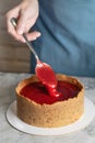 Woman making cheesecake, spoons out strawberry confiture, close up photo Royalty Free Stock Photo