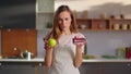 Woman making choice between apple and cake on kitchen. Woman choosing apple Royalty Free Stock Photo