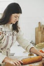 Woman making christmas gingerbread cookies in modern white kitchen. Hand kneading gingerbread dough on wooden board with flour, Royalty Free Stock Photo