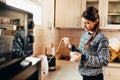 Woman making coffee drink at home kitchen using electric milk frother drink mixer coffee whisk for frothy cream whipped coffee.