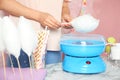 Woman making cotton candy using modern machine at table Royalty Free Stock Photo