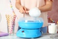 Woman making cotton candy using modern machine at table Royalty Free Stock Photo