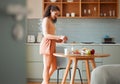 Woman making a cup of tea to relax, enjoying morning and breakfast at home, standing in kitchen. Female starting new day