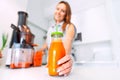 Woman making fresh carrot juice in a juicer. Bottle of homemade carrot juice Royalty Free Stock Photo