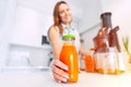 Woman making fresh carrot juice in a juicer. Bottle of homemade carrot juice Royalty Free Stock Photo