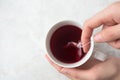 Woman making fruity tea in tea pyramid bag in white cup on marble background. Cozy winter breakfast mood Royalty Free Stock Photo