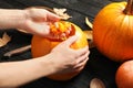 Woman making Halloween pumpkin head jack lantern on wooden table Royalty Free Stock Photo