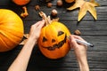 Woman making Halloween pumpkin head jack lantern on wooden table Royalty Free Stock Photo