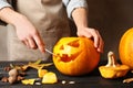 Woman making Halloween pumpkin head jack lantern on wooden table Royalty Free Stock Photo