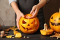 Woman making Halloween pumpkin head jack lantern on wooden table Royalty Free Stock Photo