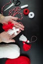 Woman making handmade traditional martisor, from red and white strings with tassel. Symbol of holiday 1 March, Martenitsa, Baba