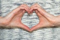 Woman making heart shape with hands. Casual jumper.