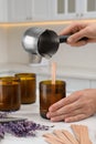 Woman making homemade candle at table in kitchen, closeup Royalty Free Stock Photo