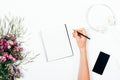 Woman making notes on blank sheet among pink flowers